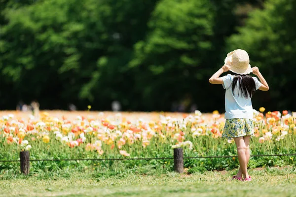 花畑を眺める少女の後ろ姿。帽子をかぶっているbyフリー素材ぱくたそ［-httpswww.pakutaso.com-］